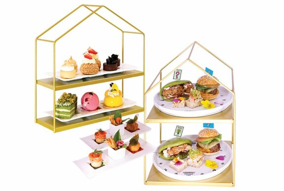 Two-tiered house-shaped serving platters filled with decadent high tea treats.