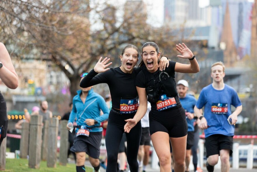 Two girls with arms around each other making faces on a fun run.
