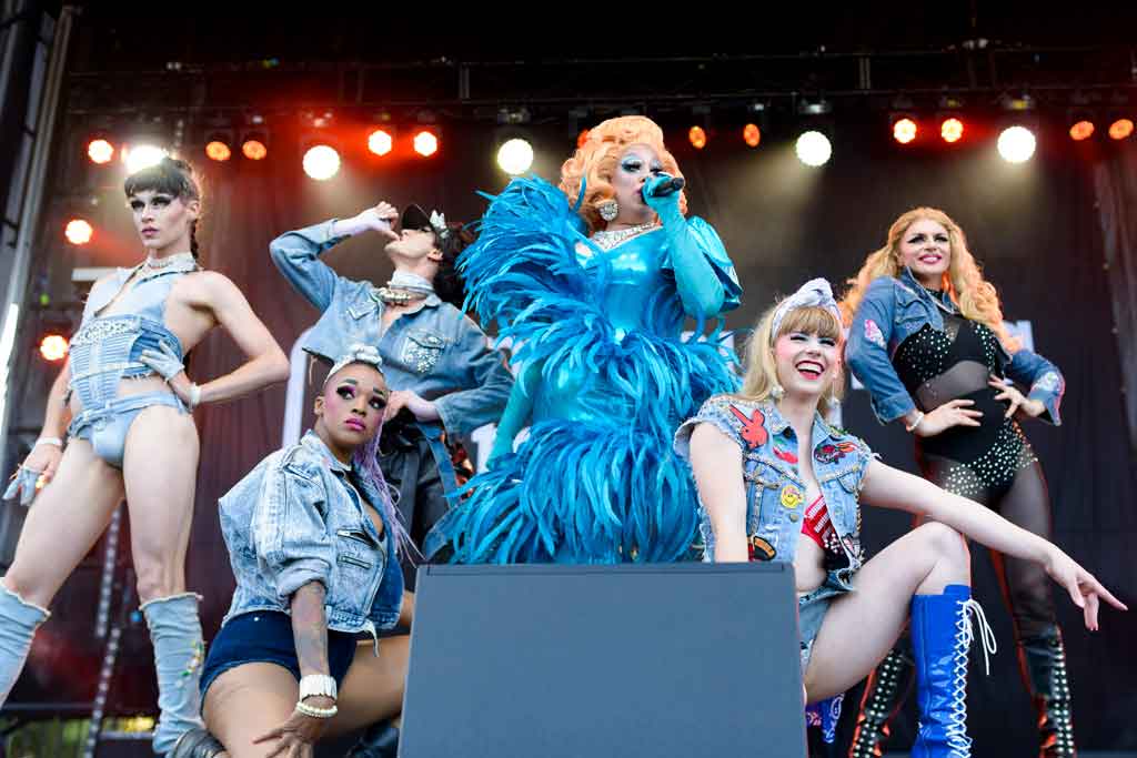 Five performers in drag posed on a stage
