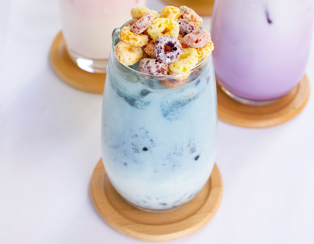 A blue latte in a glass topped with cereal