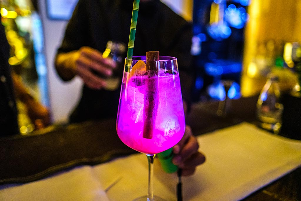 Bright purple coloured drink with garnish on a bar 