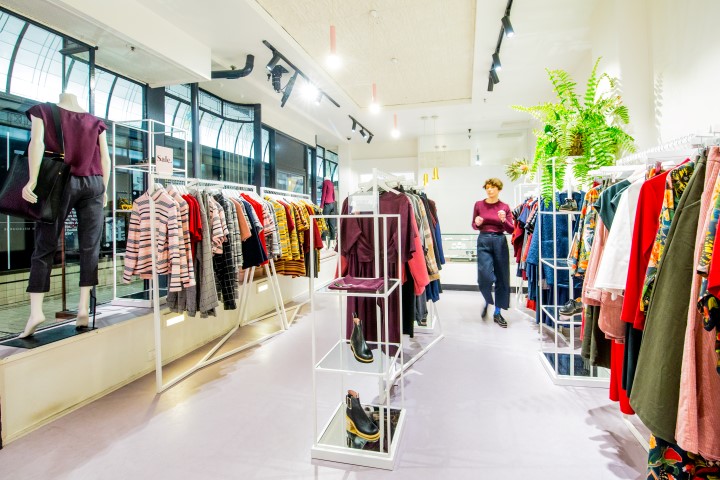 a women's clothes shop showing racks of brightly coloured clothing and shelves of shoes