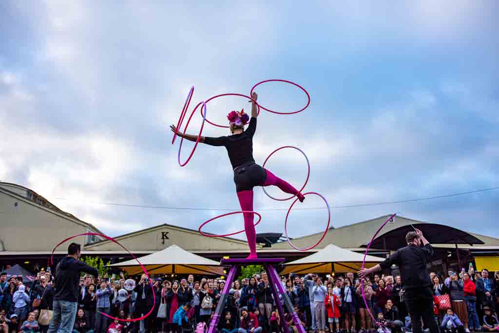 A street performer spinning various hoops on their body 