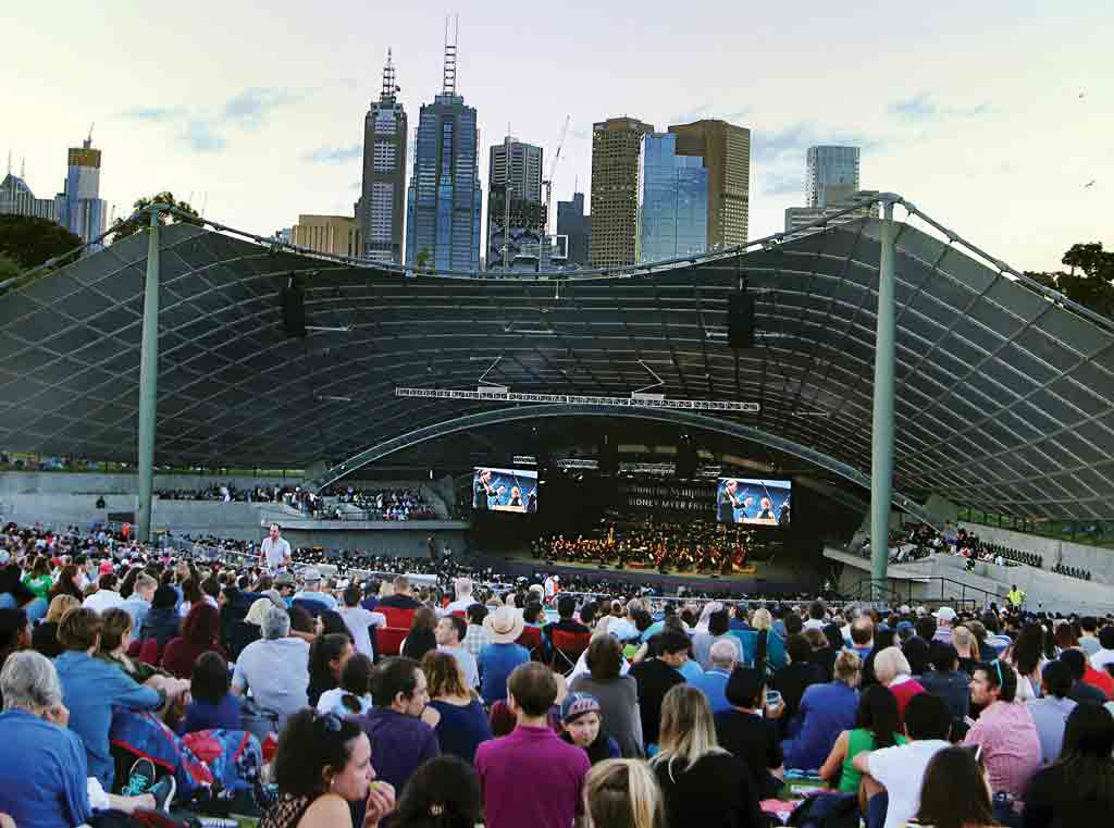 A crowd of people outdoors surrounding a large stage