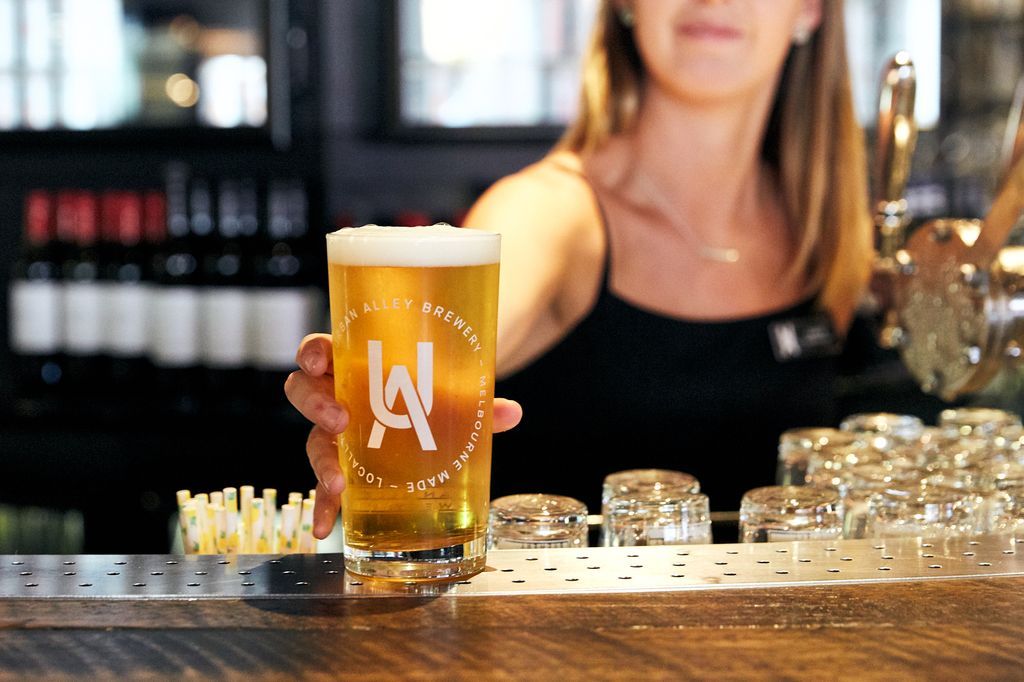 A woman putting a glass of beer down on a bar
