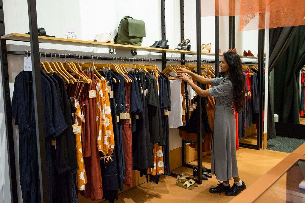 A woman browsing a rack of clothes in a shop