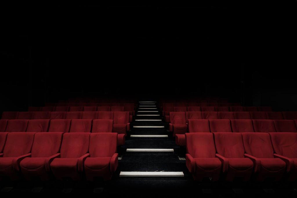 A theatre filled with empty red chairs