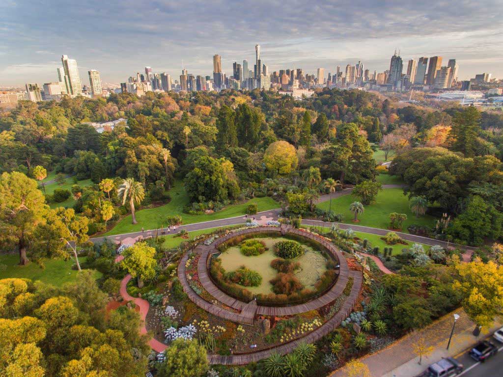 An aerial view of a huge landscaped garden with the city skyline in the background