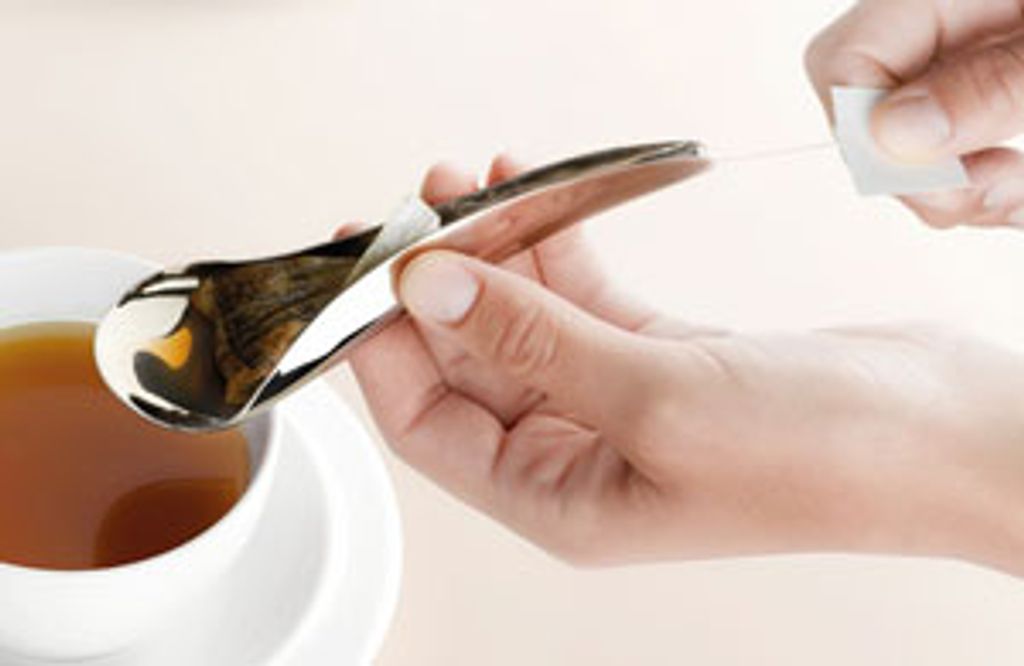 A silver spoon with a tea bag in it
